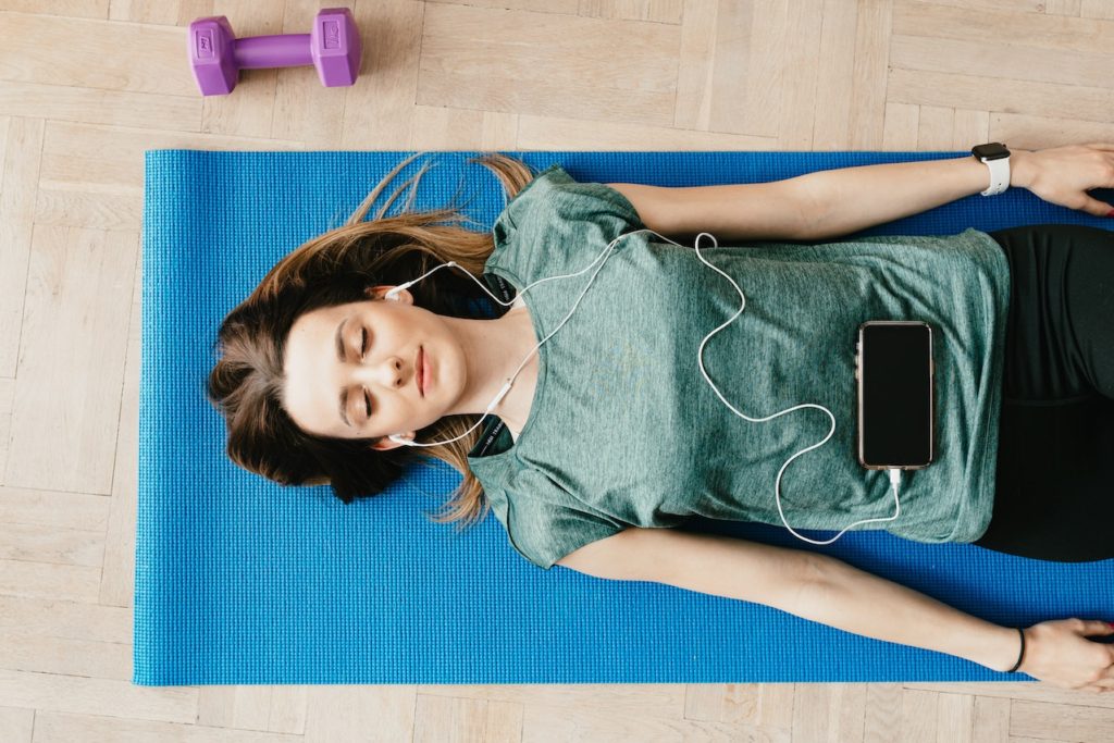 woman listening to music on yoga mat